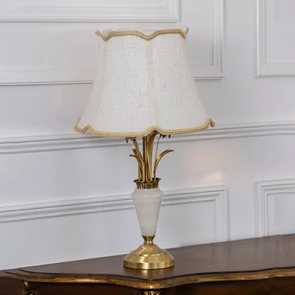 Gold and white marble base table lamp with cream fabric shade turned off against white background home decor table lamp.
