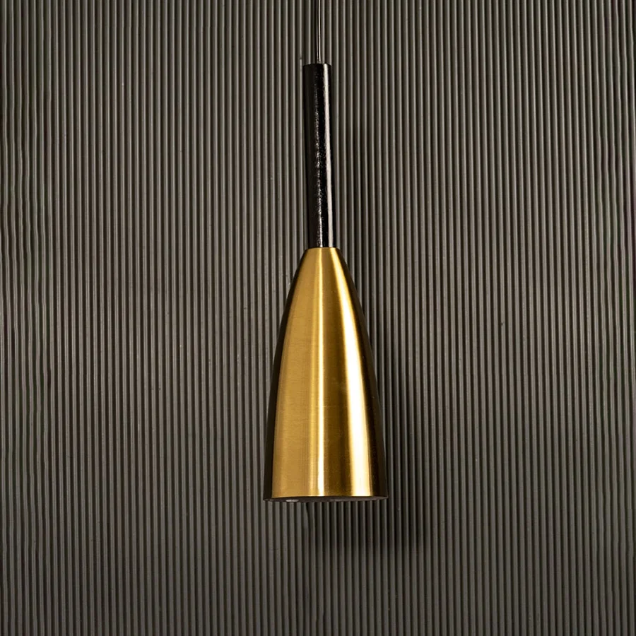 A metal pendant light glowing softly against a ribbed dark backdrop creating elegant focused illumination and minimal refined décor.