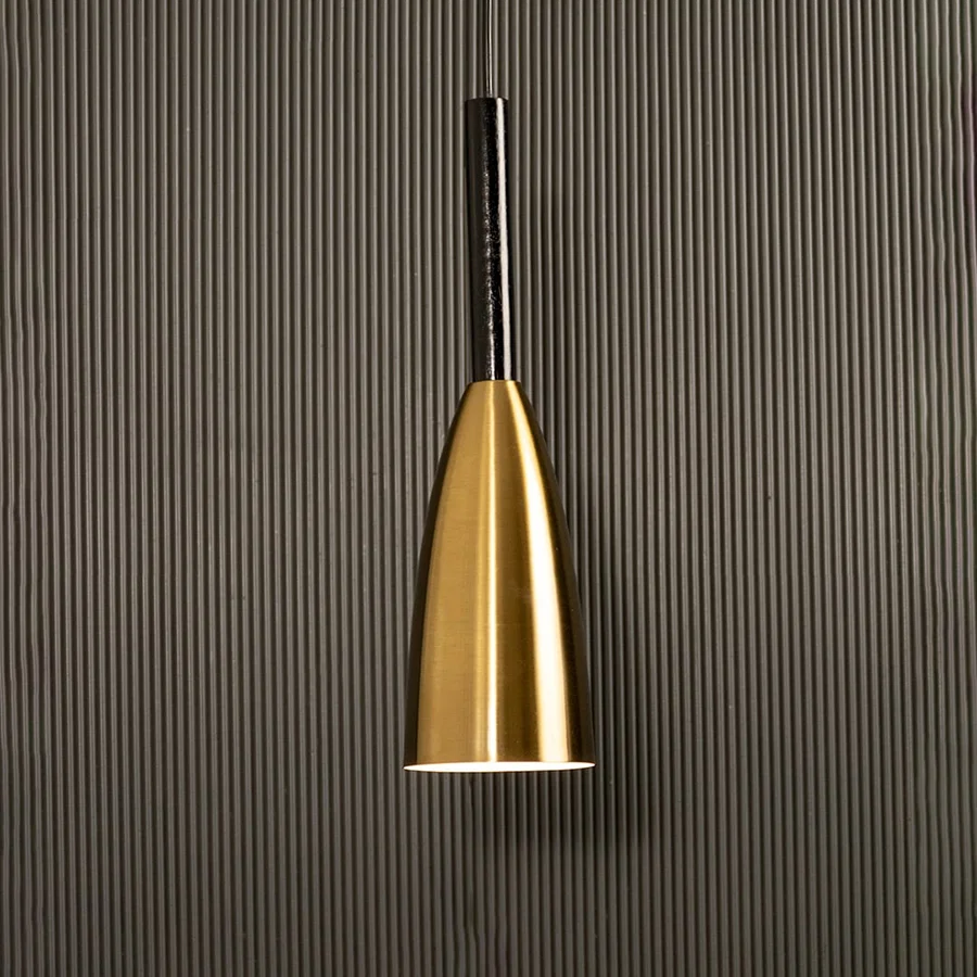 A slim metal pendant light shining softly against a ribbed dark backdrop creating elegant focused illumination and minimal refined modern décor.
