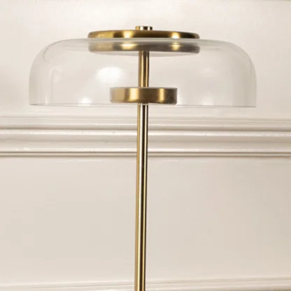 Closeup of gold and clear glass dome table lamp highlighting its polished metal finish sleek stem and smooth transparent shade.
