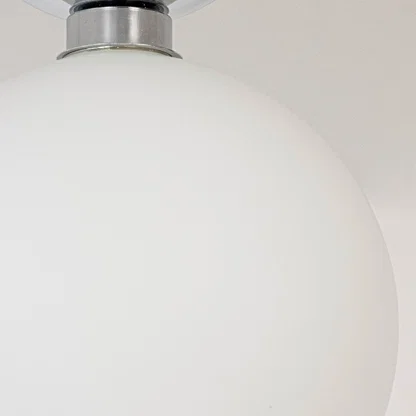 Closeup of ceiling light with chrome finish base and frosted glass globe shade for stylish modern home lighting.