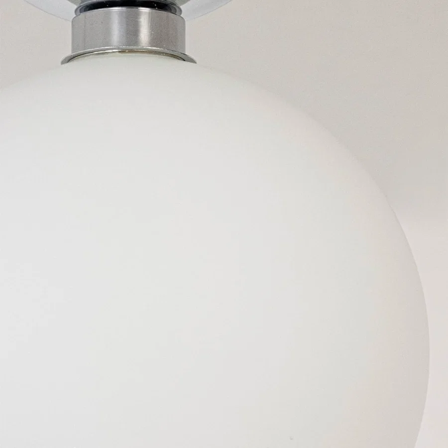 Closeup of ceiling light with chrome finish base and frosted glass globe shade for stylish modern home lighting.