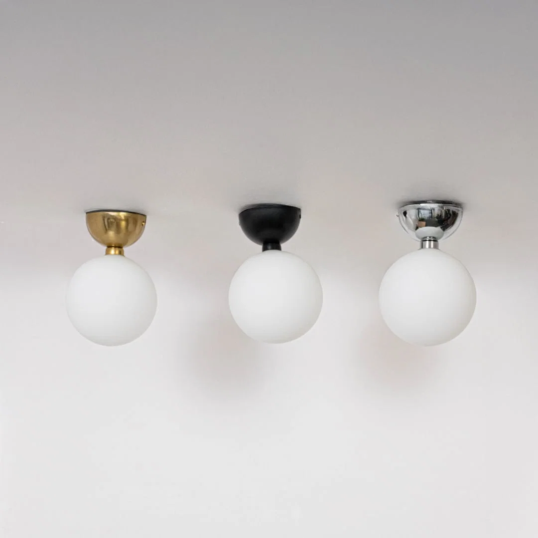 Collection of ceiling lights in chrome gold and black finish with frosted glass globes shown switched off on background.