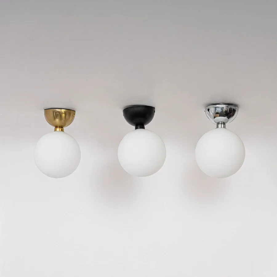Collection of ceiling lights in chrome gold and black finish with frosted glass globes shown switched off on background.