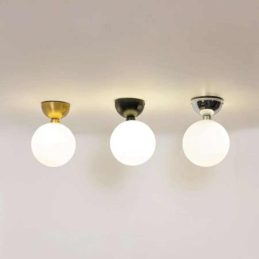 Set of ceiling lights in chrome gold and black finish with frosted glass globe shades glowing on white background.