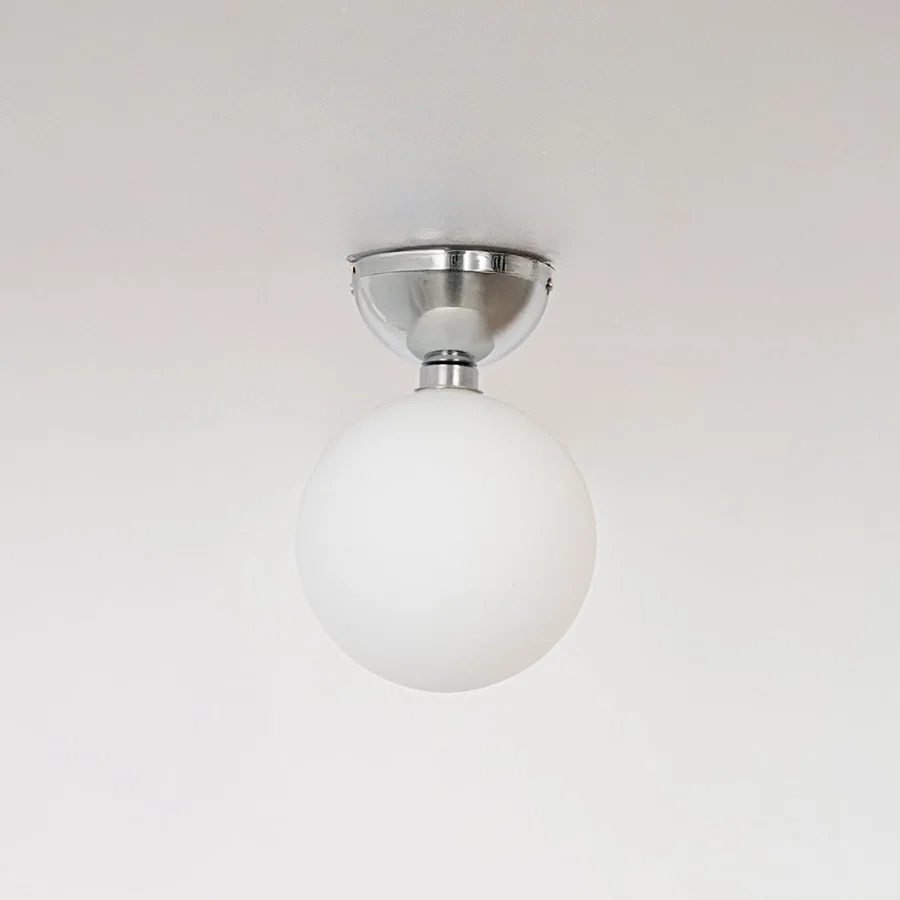 Ceiling light with polished chrome base and frosted glass globe shade shown off on plain white background.