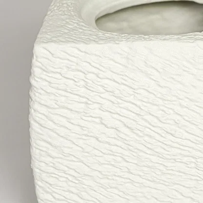 Close up view white textured ceramic planter showing rough sculpted surface matte finish decorative ceramic accent.