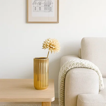 A glossy gold ribbed vase styled in a soft minimal setting creating a warm elegant lifestyle look that highlights its modern reflective finish.