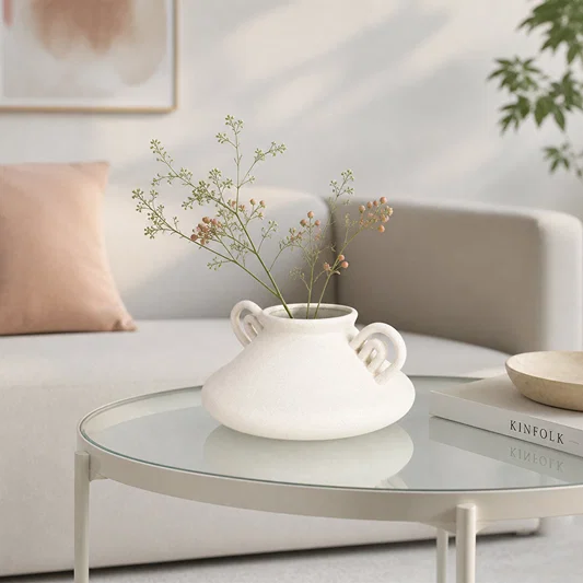 White ceramic flower vase with dried blooms placed on glass table for stylish contemporary home decor.