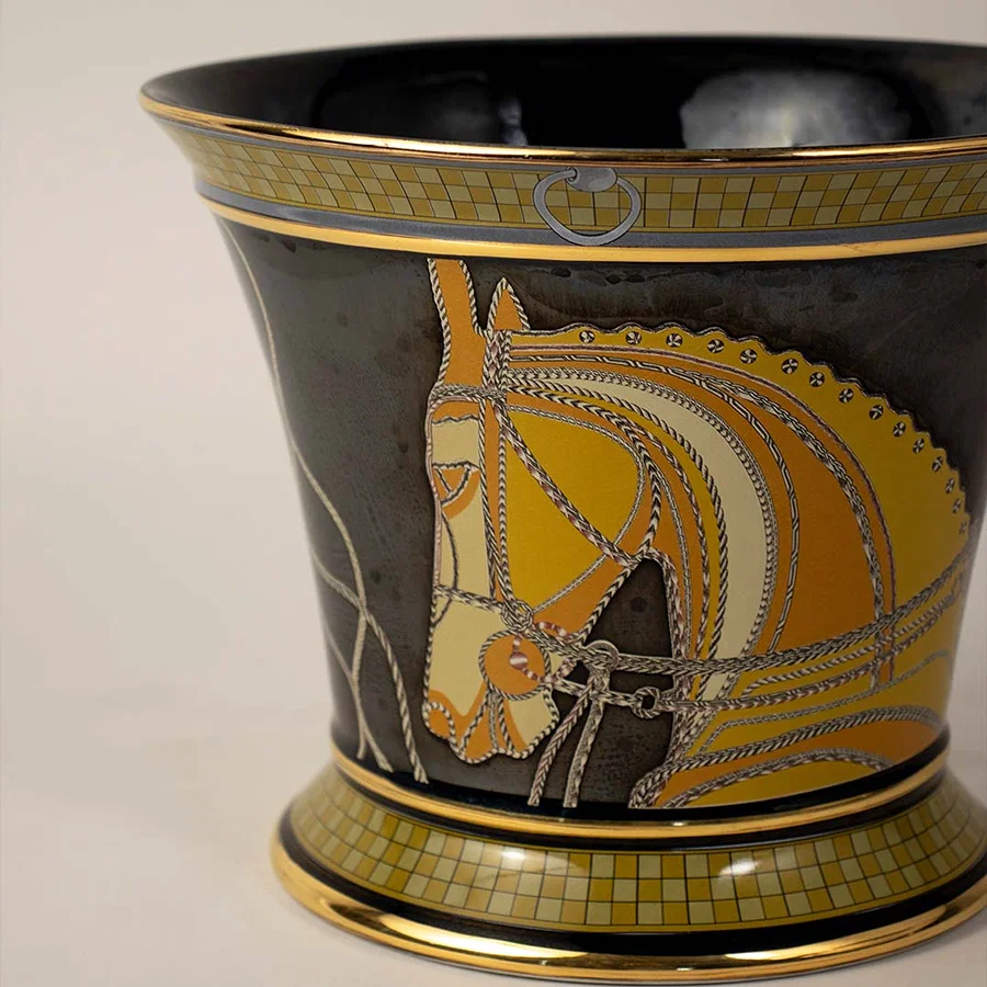 Decorative ceramic vase with intricate yellow and black artwork pattern placed on white surface against neutral background showcasing traditional artistic home decor appeal.