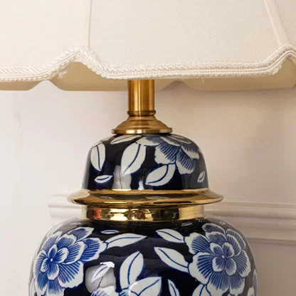 Blue floral ceramic table lamp showcasing intricate hand painted craftsmanship with brass accents and fabric shade design.