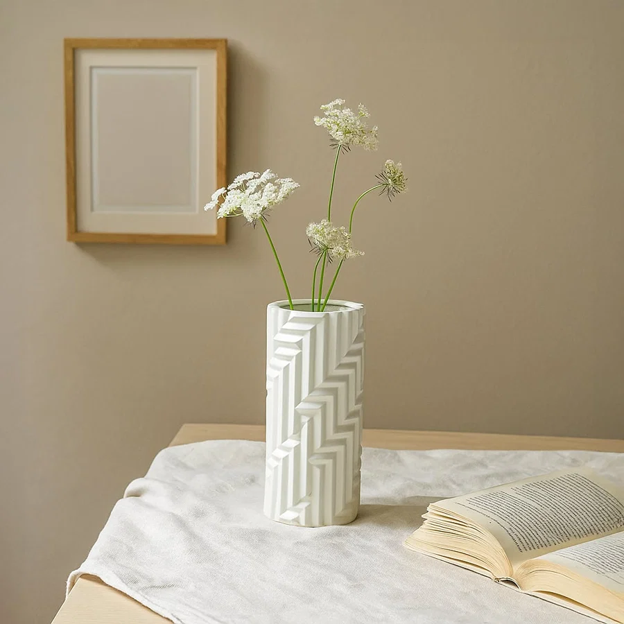A tall white textured vase displayed in a soft minimal setting creating a clean modern lifestyle look for contemporary home decor.