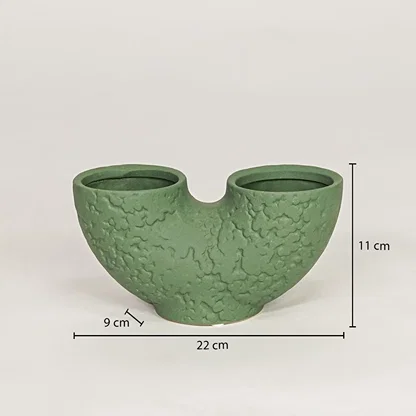 Green ceramic dual flower vase measuring 11 cm height and 22 cm width for modern tabletop decor placement.