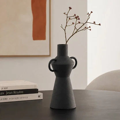 Black textured ceramic flower vase with dried branches placed on table for modern home decor styling.
