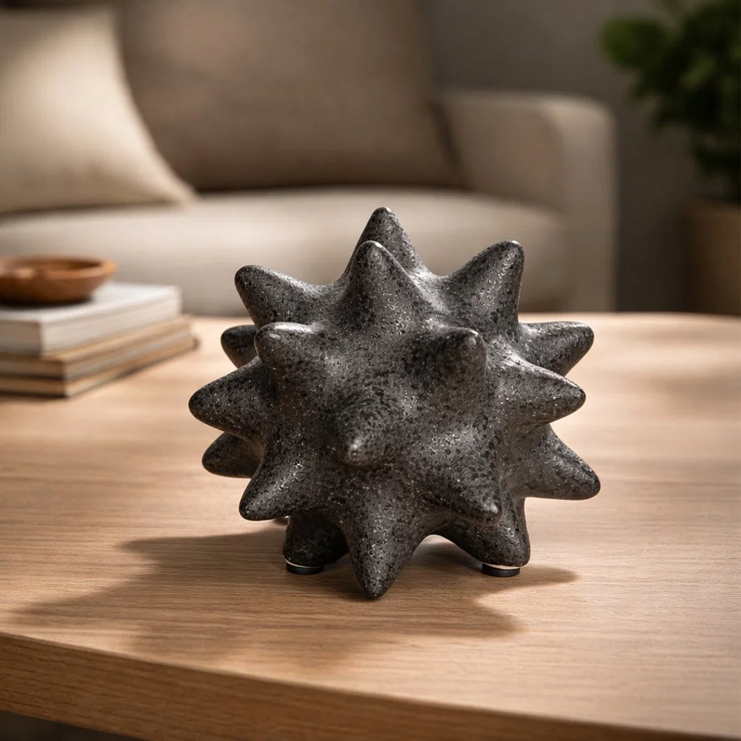 Black textured ceramic decorative object with spiked sculptural design styled on wooden coffee table in warm modern living room.