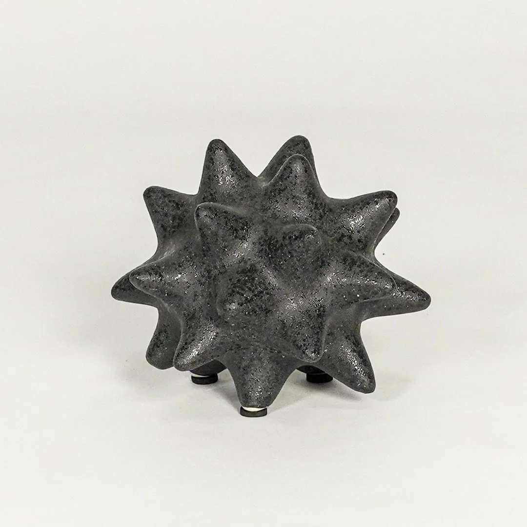 Modern black ceramic statement decor accent with starburst inspired sculpted shape for contemporary interiors.