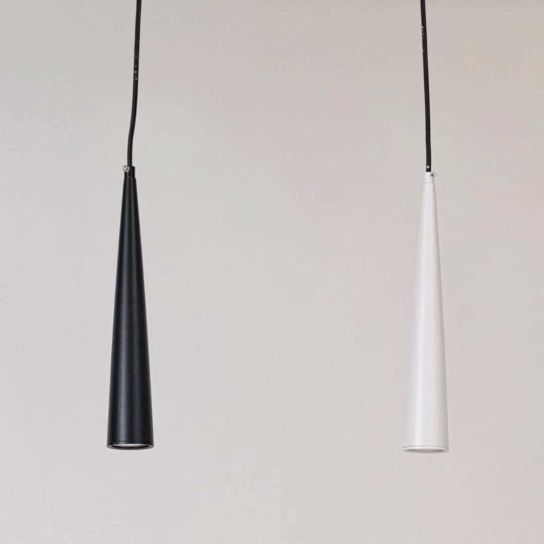 Pair of black and white metal cone pendant lights designed for elegant dining room interiors.