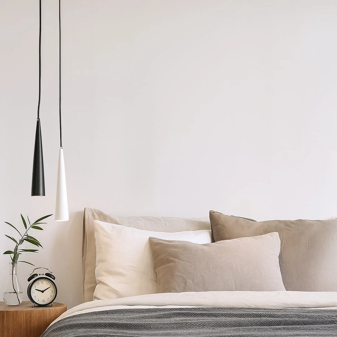 Black metal cone pendant light adding contemporary style above the bedside in modern interiors.