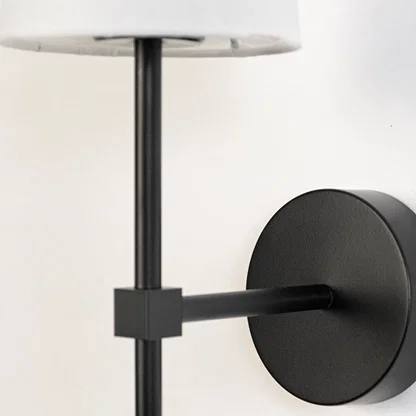 Detailed closeup of white fabric cylindrical shade and matte black metal rod hardware on contemporary minimalist wall sconce.