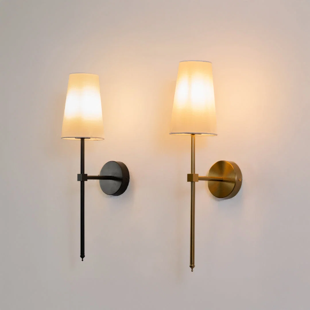 Minimal wall light in black and gold metal finish with fabric shade for bedroom or living decor lighting white background.