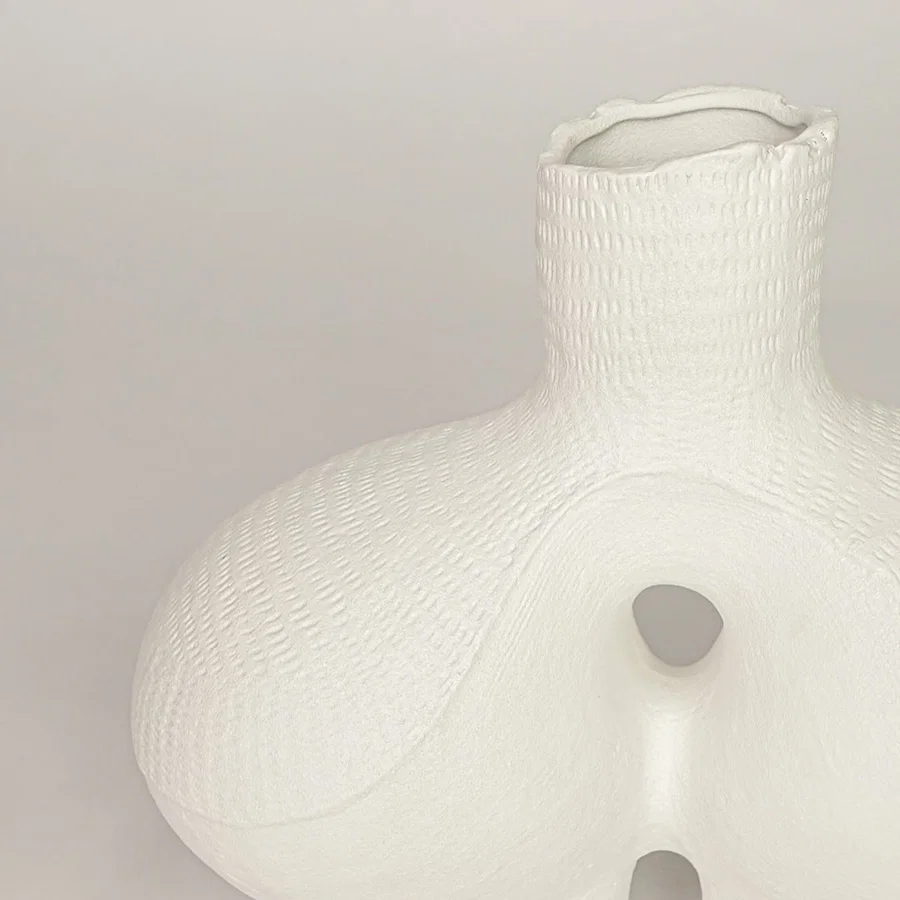 Closeup of white ceramic vase with sculpted textured finish for elegant tabletop and shelf decor styling ideas.