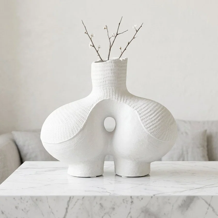 White ceramic flower vase with sculpted artistic design for elegant modern tabletop and shelf decor styling.