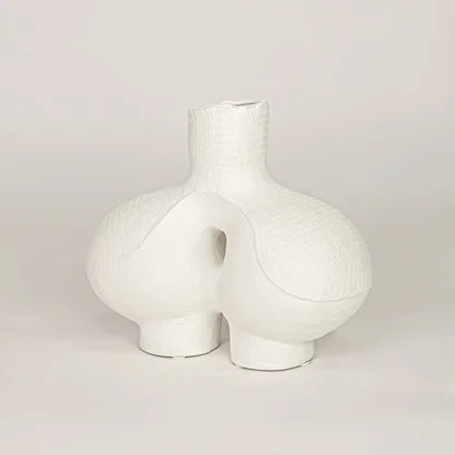 White ceramic decorative vase with sculpted artistic design for modern tabletop shelf and console decor placement.