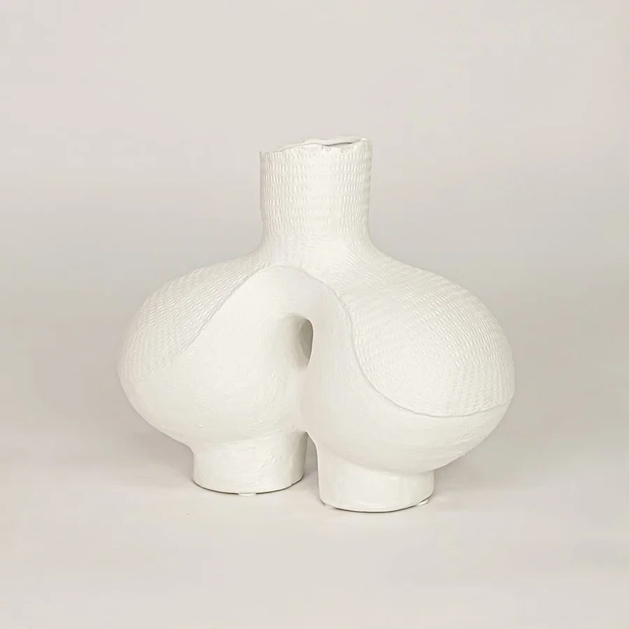 White ceramic decorative vase with sculpted artistic design for modern tabletop shelf and console decor placement.