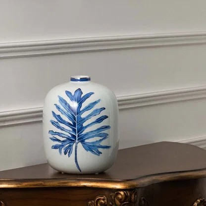 White ceramic jar with blue leaf artwork in a front view perfect for modern décor styling and fresh interior accents.