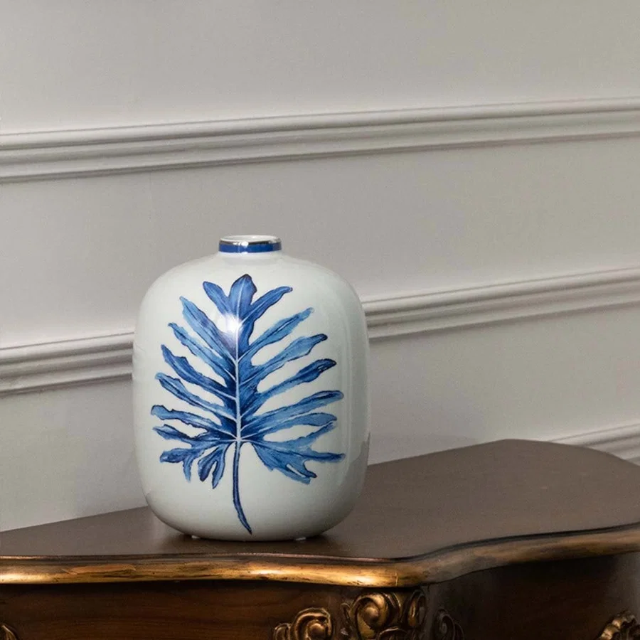 White ceramic jar with blue leaf artwork in a front view perfect for modern décor styling and fresh interior accents.