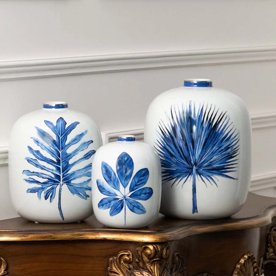 Pair of white ceramic jars with blue leaf artwork in a front view perfect for fresh décor styling and contemporary home accents.