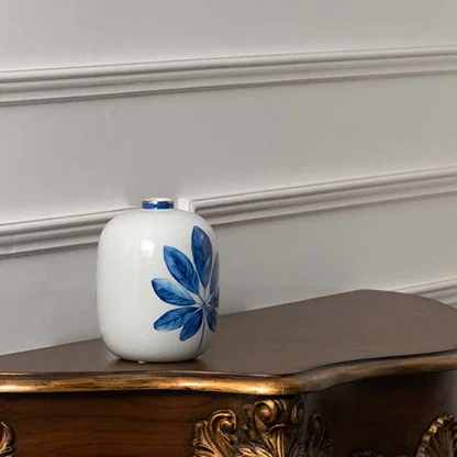 White ceramic jar with single blue leaf artwork in a front view ideal for minimalist décor styling and clean decorative display.
