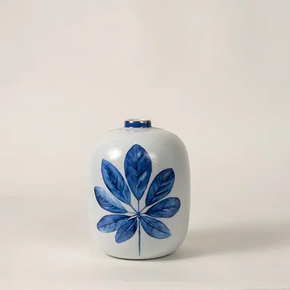 White ceramic decorative jar with blue botanical artwork for contemporary tabletop styling and elegant home decor displays.