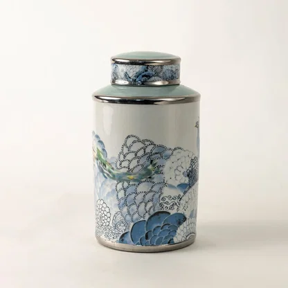 White ceramic decorative jar with blue wave pattern and silver lid for sophisticated tabletop styling and home decor.
