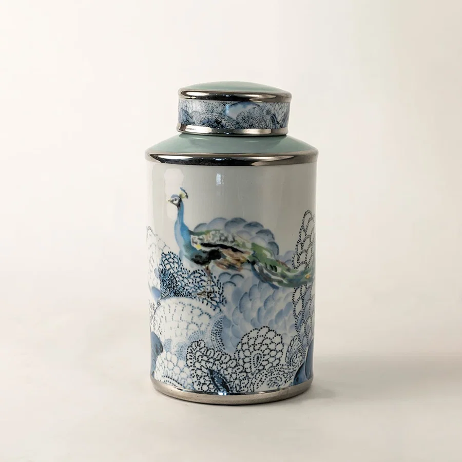 Blue and white ceramic jar with fish artwork shown on plain background for coastal inspired décor.