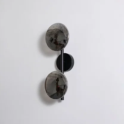 Contemporary black metal dual globe wall light fixture with smoked glass shades turned off on clean white background.