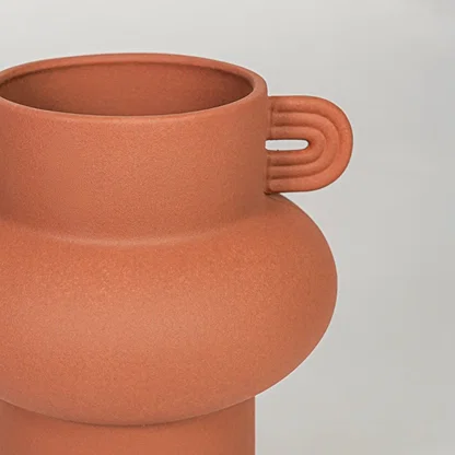 Orange ceramic flower vase closeup with matte finish modern decorative vase for shelf console living room decor styling.