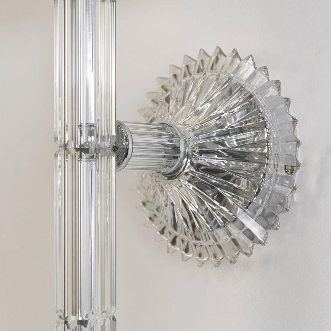 Closeup of wall light with chrome base fabric shade and crystal drop accent for modern home decoration.
