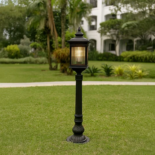Outdoor garden post light in black metal with glass panels placed on lawn pathway providing warm illumination and classic landscape lighting style.