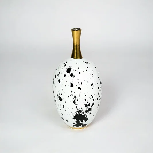 White ceramic vase with gold neck for stylish table placement and modern indoor home decor styling accent piece.
