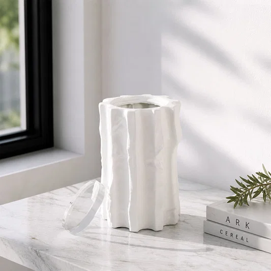 White textured ceramic vase placed on marble table for elegant modern home decor styling near window.