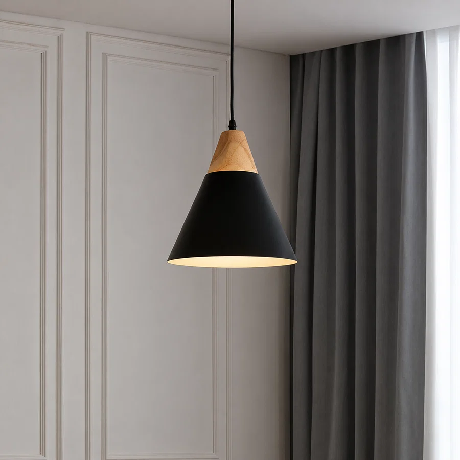 A modern pendant light with a matte black cone shade and a natural light wood top, hanging in a room with gray curtains and white paneled walls.