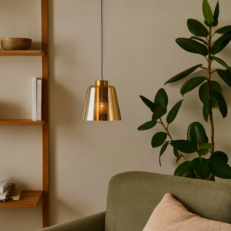 Gold metal pendant light hanging beside indoor plant adding modern elegance and warm ambient lighting to living room.