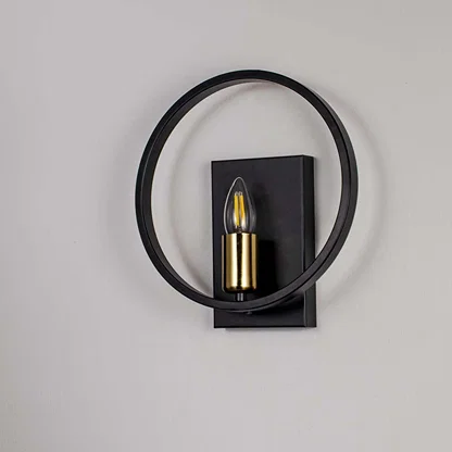 Modern wall light with matte black circular frame and gold bulb holder shown off on white background for stylish interiors.