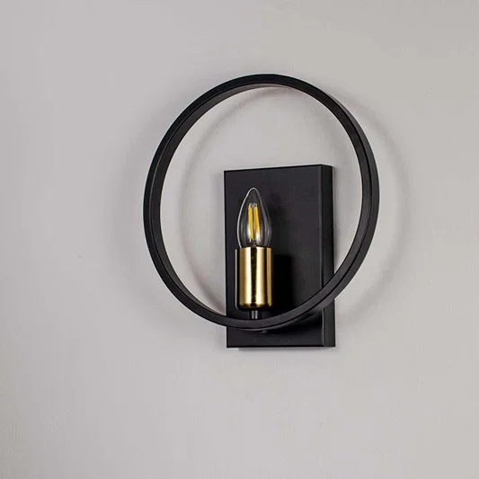 Modern wall light with matte black circular frame and gold bulb holder shown off on white background for stylish interiors.