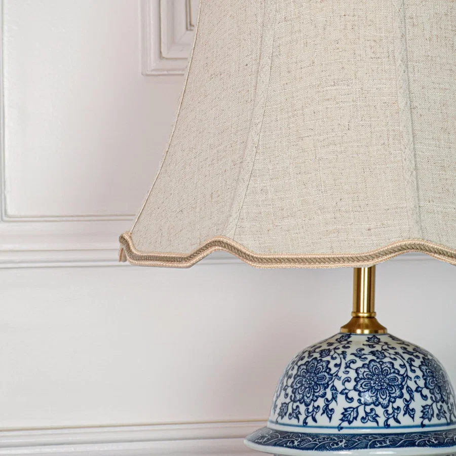 Closeup of blue white ceramic table lamp showing detailed floral pattern smooth glaze finish and brass metal base.