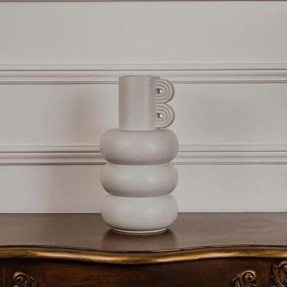 A contemporary neutral vase presented on a clean white background with its bold stacked form and artistic side accent standing out clearly.