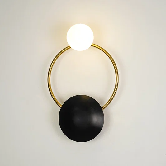 Contemporary gold brass hoop wall sconce featuring an illuminated frosted glass globe bulb on a white backdrop.