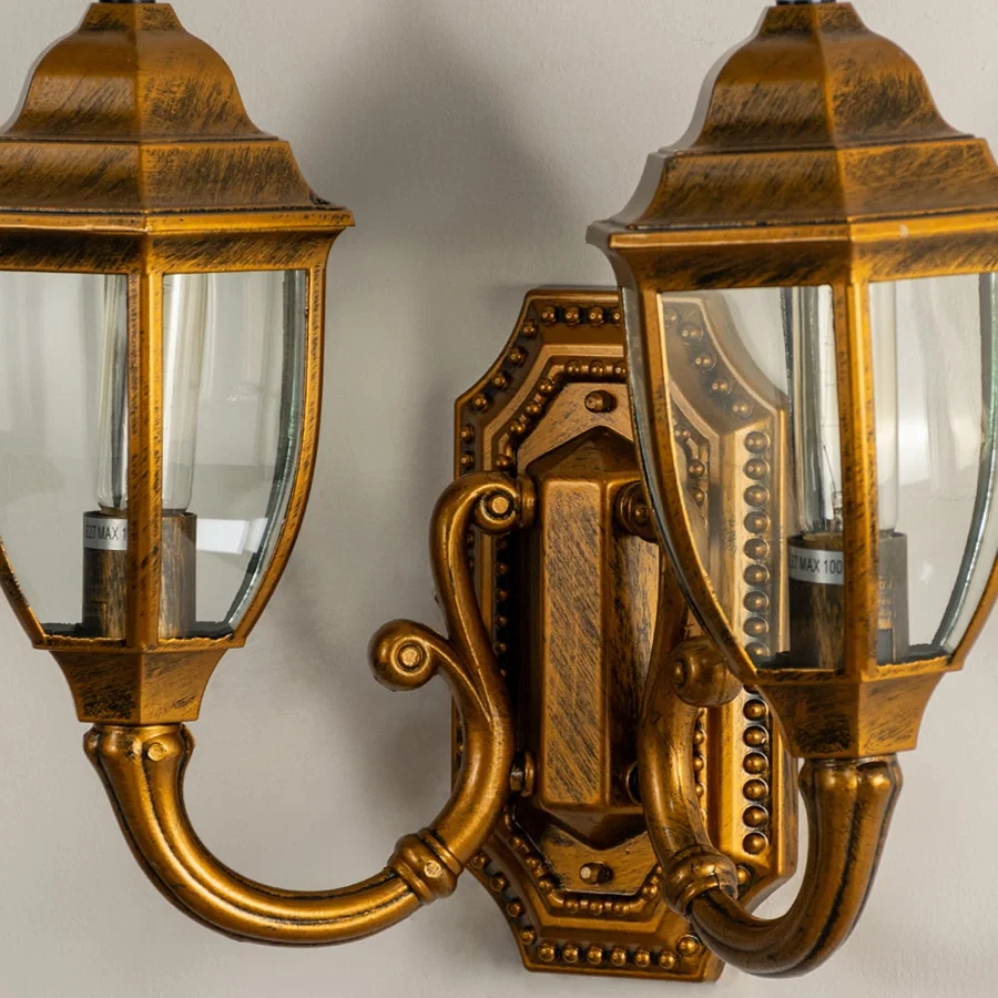 Closeup view of double brass outdoor lantern showing glowing bulbs clear glass panels and antique metal finish for warm elegant entrance lighting.