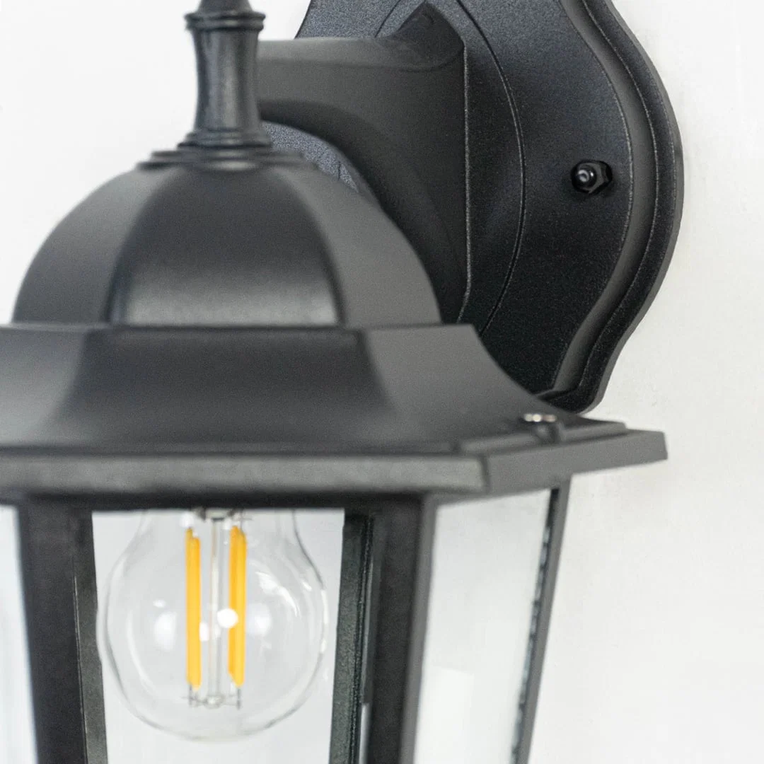 Closeup of classic outdoor wall lantern showing refined black metal detailing and transparent glass panes for clear brightness.